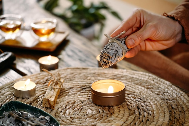 Mains de femme brûlant de la sauge blanche avant le rituel sur cadle