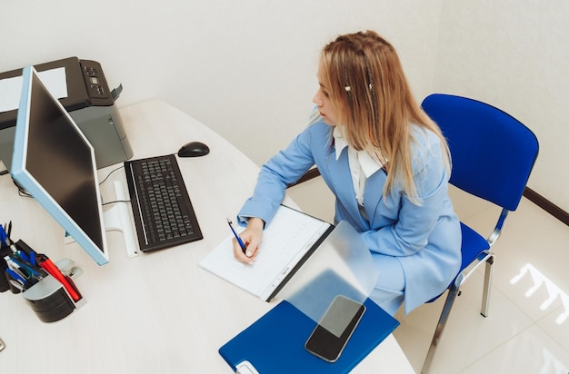 Les mains d'une femme de bureau tapant sur le clavier femme blonde travaillant au bureau