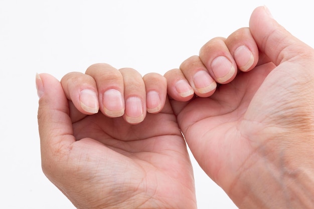 Mains de femme caucasienne recadrée montrant des ongles sains et soignés sans vernis sur fond blanc