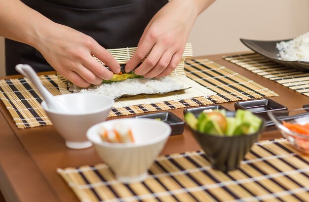 Mains de femme chef enroulant un sushi japonais