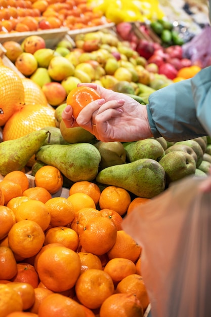 Mains d'une femme choisissant la mandarine au marché de fruits et légumes