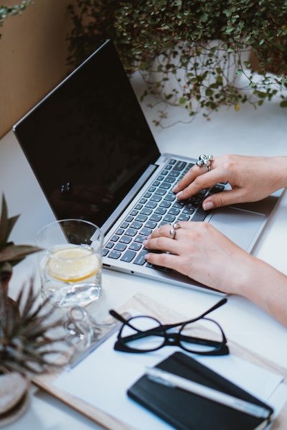 Mains de femme sur un clavier d'ordinateur portable lieu de travail confortable