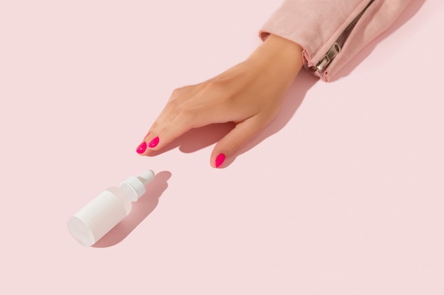 Photo mains de femme avec compte-gouttes de sérum sur fond rose concept de traitement de beauté soins du corps