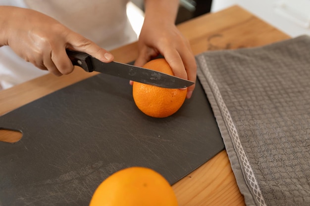 Les mains d'une femme coupant une orange