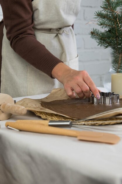 Les mains de femme coupent des biscuits de Noël sur la table