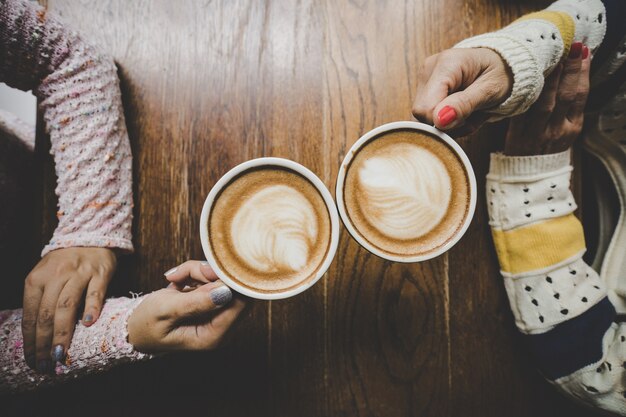 Mains de femme couple tenant une tasse de café sur la table en bois