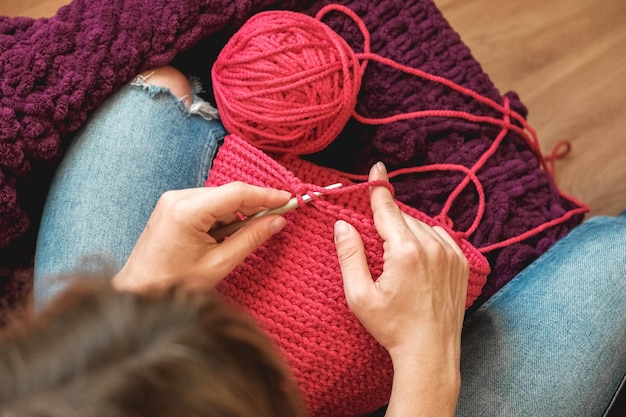 Mains femme dans une maison confortable tricote à partir d'un fil rose. Vue de dessus. Copie, espace vide pour le texte.