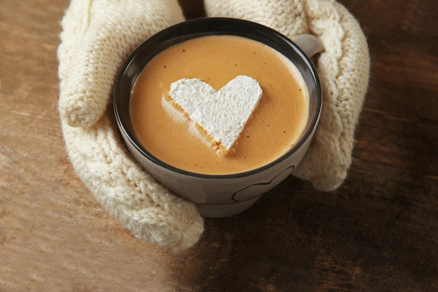 Mains de femme dans des mitaines tenant une tasse de café