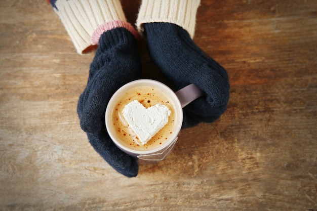 Photo mains de femme dans des mitaines tenant une tasse de café