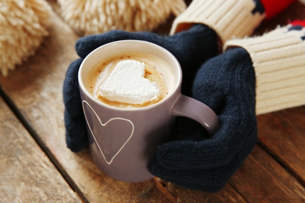 Mains de femme dans des mitaines tenant une tasse de café