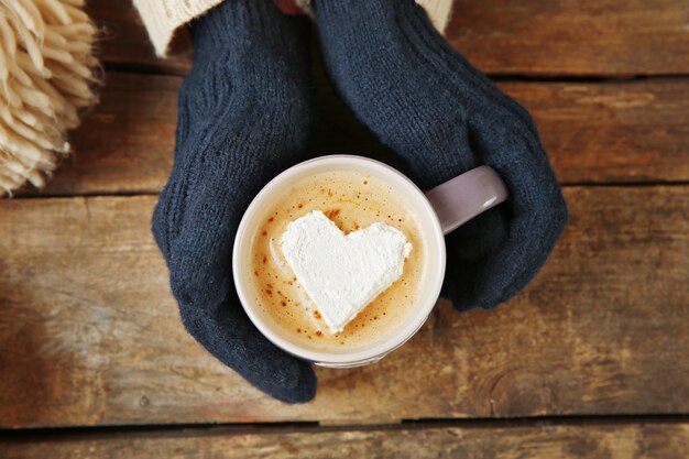 Mains de femme dans des mitaines tenant une tasse de café