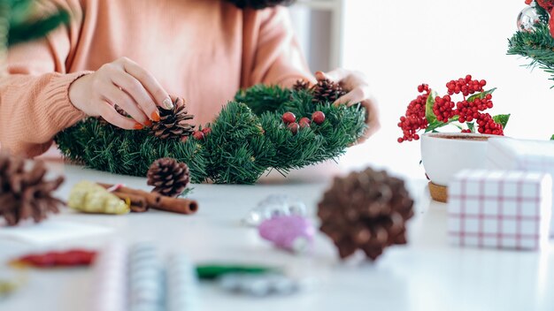 Photo mains de femme décorer le sapin de noël et la guirlande de noël.