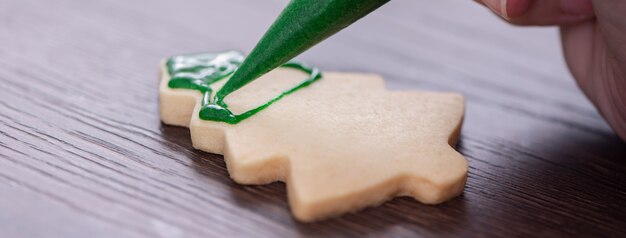 Mains de femme dessinant un biscuit de Noël en pain d'épice