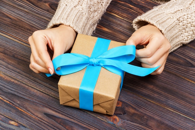 Des mains de femme donnent des cadeaux emballés à la main pour la Saint-Valentin ou d'autres fêtes en papier avec ruban bleu