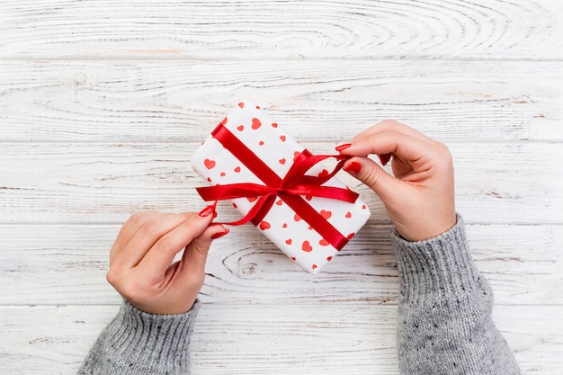 Mains de femme donnent des cadeaux emballés à la main pour la Saint-Valentin ou d'autres fêtes en papier avec ruban rouge