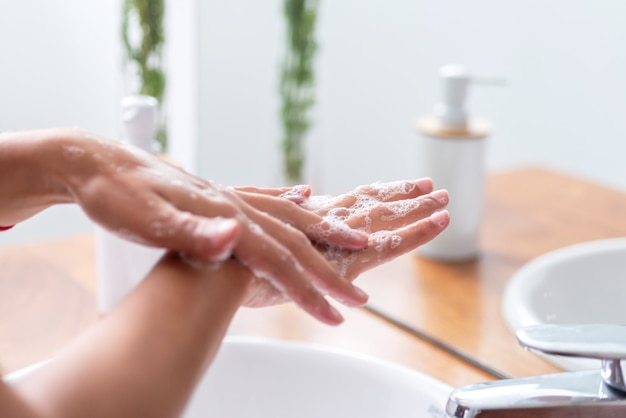 Mains de femme avec du savon et se laver les mains sous le robinet d'eau