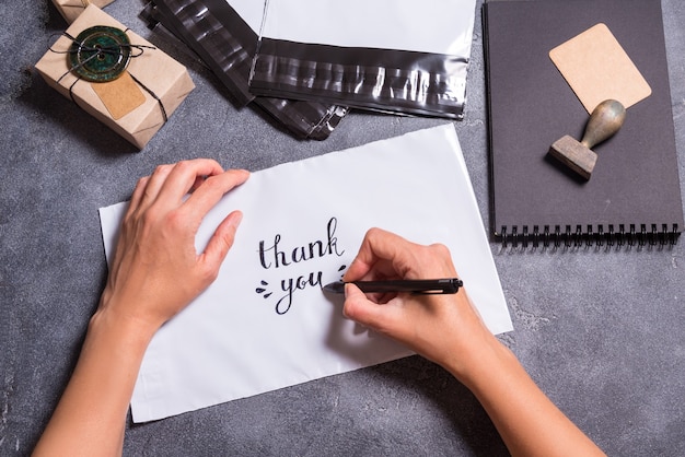 Mains de femme écrit Merci texte sur enveloppe en polyéthylène