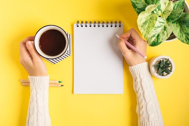 Mains de femme écrivant dans le bloc-notes.