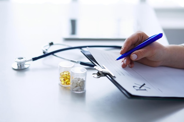 Mains de femme écrivant sur une feuille de papier dans un presse-papiers avec un stylo isolé sur un bureau