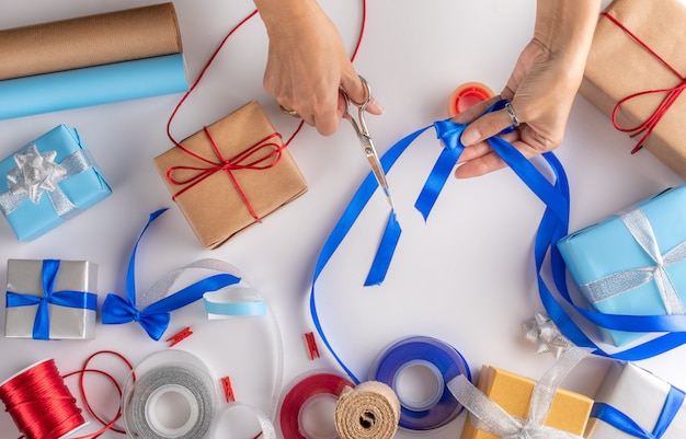 Mains d'une femme emballant des cadeaux de Noël - ustensiles nécessaires pour emballer des cadeaux.