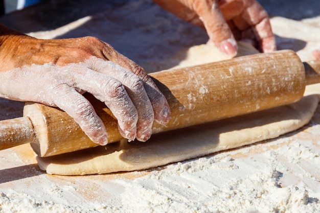 Mains de femme étalant une pâte avec un rouleau à pâtisserie