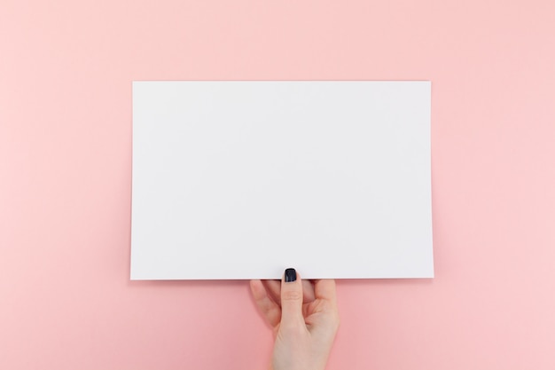 Mains de femme avec une feuille de papier A4 vierge