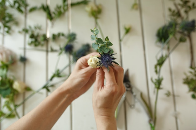 Des mains de femme fleuriste recueille des fleurs pour boutonnière marié. Flux de travail du fleuriste