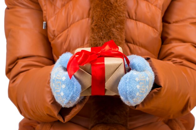 Les mains de la femme avec des gants d'hiver tenant une boîte-cadeau rouge de Noël.