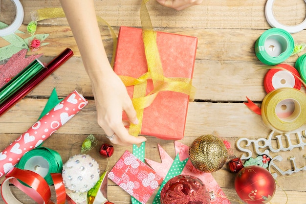 Les mains d'une femme inconnue décorent le cadeau de Noël.