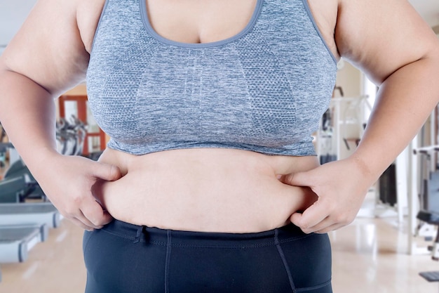 Les mains d'une femme inconnue lui pincent la graisse du ventre