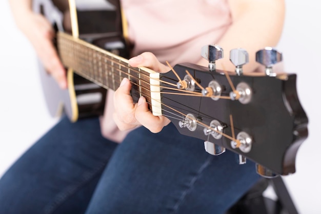 Mains de femme jouant de la guitare acoustique, gros plan