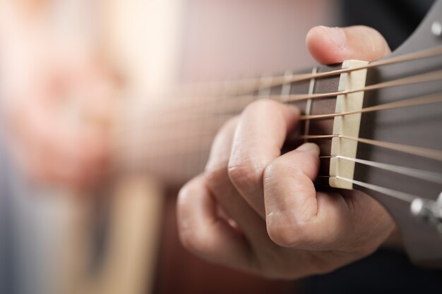 Mains de la femme jouant de la guitare acoustique.