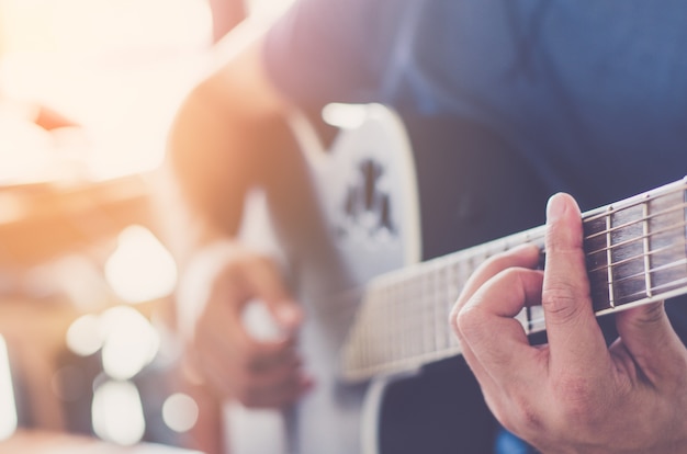 mains de la femme jouant de la guitare acoustique