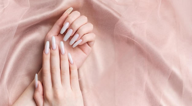 Les mains d'une femme avec une manucure dessus les ongles sont peints en blanc