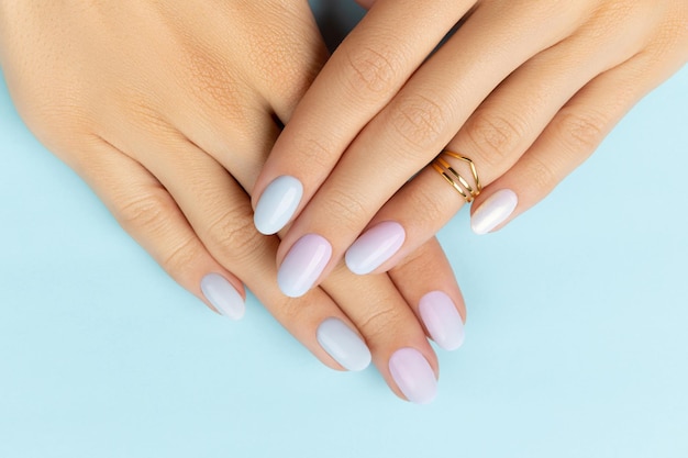 Mains de femme avec manucure à la mode sur fond bleu conception d'ongles d'été