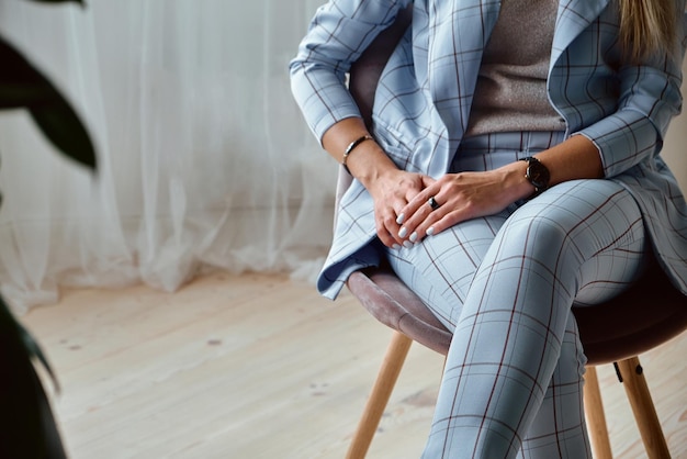 Mains d'une femme méconnaissable en costume assis sur une chaise