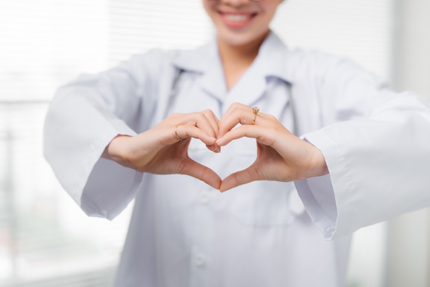 Les mains d'une femme médecin en forme de coeur se bouchent