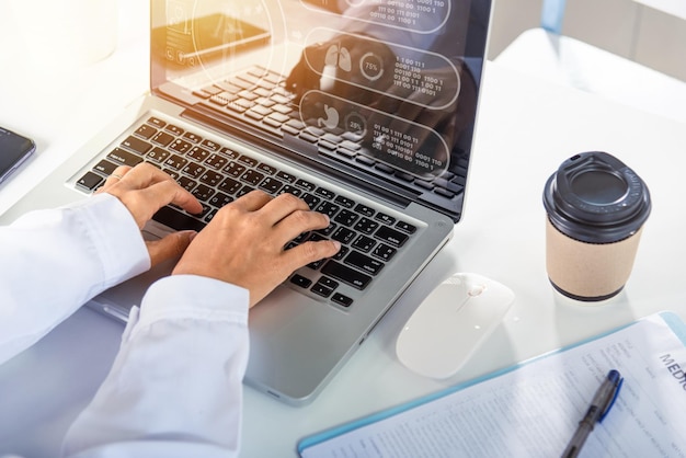 Les mains d'une femme médecin portent un uniforme à l'hôpital, elle tape des informations sur un ordinateur portable à clavier