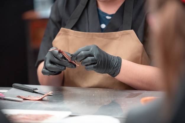 Mains de femme nettoyant un anchois. Femme travaillant avec du poisson faisant des filets d'anchois