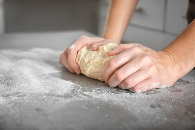 Mains de femme pétrir la pâte sur la table de cuisine