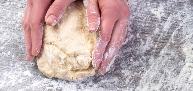 Mains de femme, pétrir la pâte sur la table