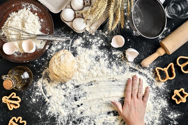 Les mains de la femme pétrissent la pâte sur la table avec des œufs de farine et des ingrédients Vue de dessus