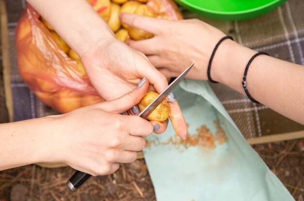 Mains de femme piler les pommes de terre préparer et éplucher les aliments sur les randonneurs de vacances en camping se préparant