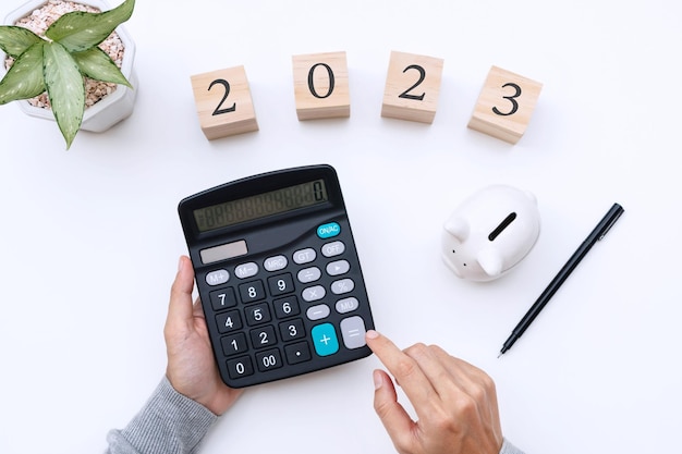 Photo mains de femme à plat à l'aide d'une calculatrice avec le numéro 2022 sur un bureau blanc objectifs du nouvel an concept de planification commerciale et financière vue de dessus de l'espace de copie