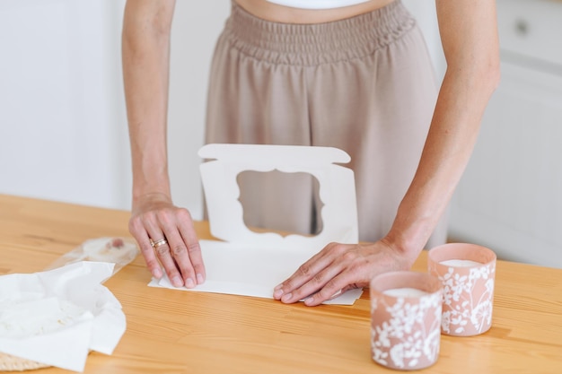 Mains de femme pliant une boîte d'emballage en papier sur la table