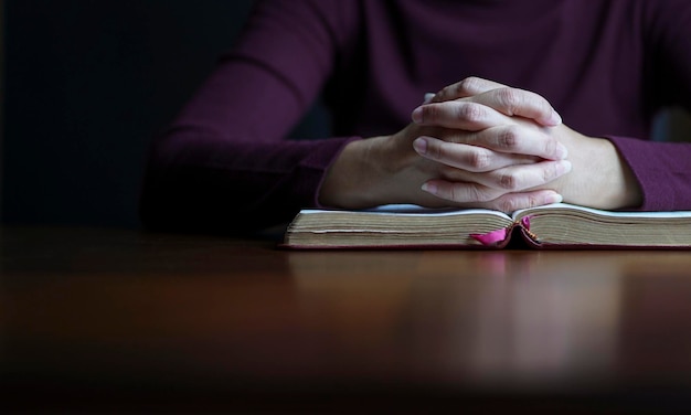 Mains de femme en posture de prière sur le dessus de la bible ouverte