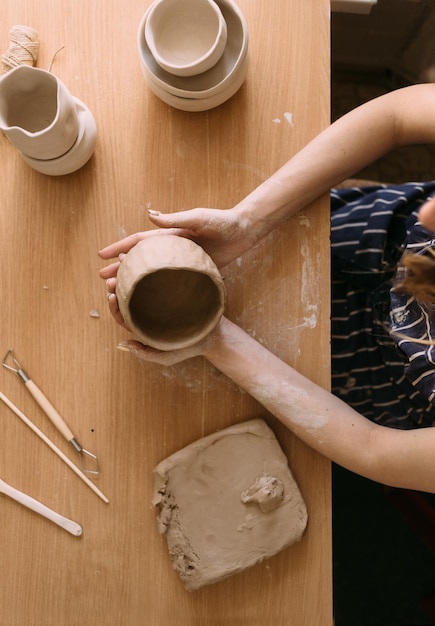 Les mains d'une femme potier travaillent avec de l'argile Nous fabriquons un bol en argile avec moulage Concept de passe-temps féminin