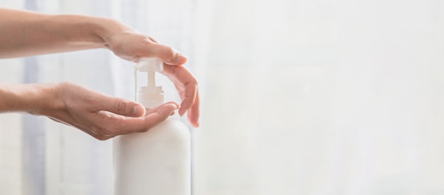 Mains de femme poussant la bouteille de savon en plastique de la pompe avec espace de copie, en utilisant le distributeur de pompe de gel désinfectant pour les mains. tuer les germes, les bactéries et les virus