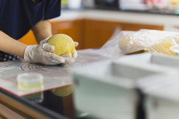 Mains de femme préparant la pâte à pain sur la table de la cuisine.