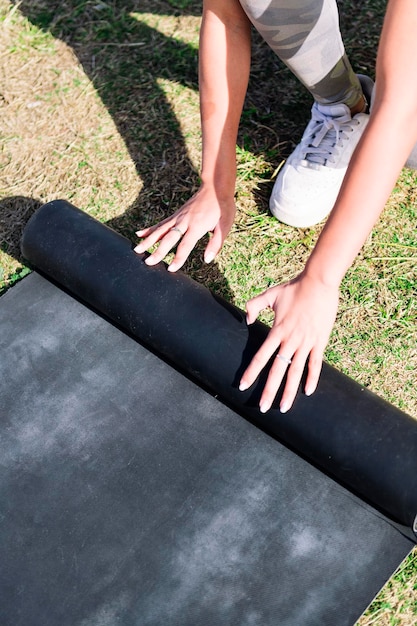 Les mains d'une femme roulant sur un tapis pour une séance de yoga